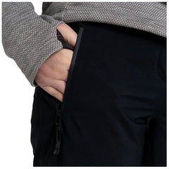 A hand is inserted in the side pocket of black pants while wearing a gray patterned long-sleeve top showcasing a close-up view of clothing and hands without any additional context.
