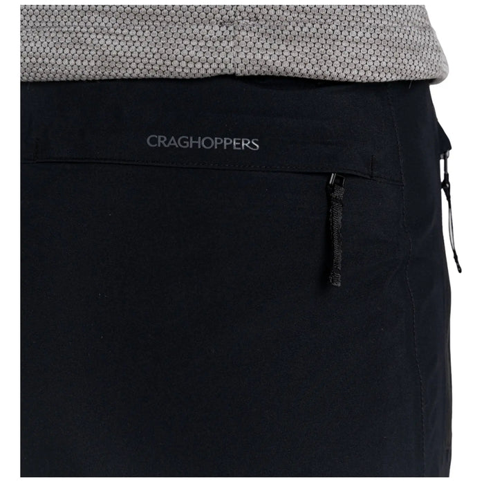 A pair of black pants is displayed with a visible zipper pocket featuring the brand name Craghoppers above it, surrounded by a textured gray fabric at the waist.