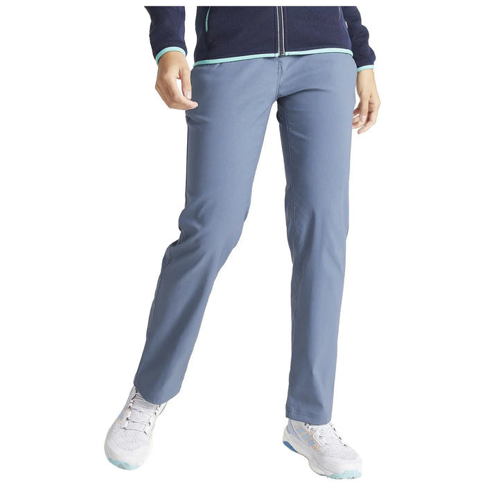 A person stands confidently wearing light blue pants and white sneakers while holding one hand on their hip against a neutral background.