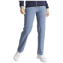 A person stands confidently wearing light blue pants and white sneakers while holding one hand on their hip against a neutral background.