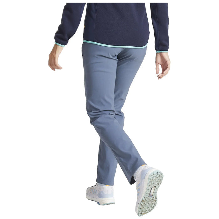 A person is walking, wearing a dark blue fleece top and light blue pants, with white athletic shoes, in a neutral background suggesting an indoor environment.