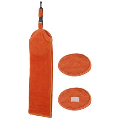 An orange towel with a hanging loop is displayed alongside two matching oval pads resting on a flat surface in a plain setting. The pads appear soft and absorbent.
