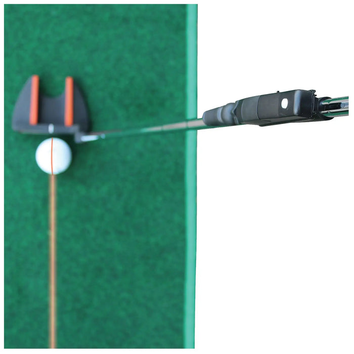 A golf putter is poised above a white golf ball with an orange line, ready to strike it on a green turf surface, indicating a practice or training setting.