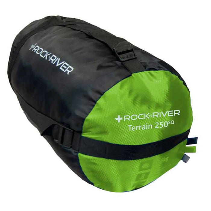 A black and green cylindrical bag labeled Rock River Terrain 250SQ is positioned upright with straps visible suggesting it is designed for outdoor use or camping in various environments.